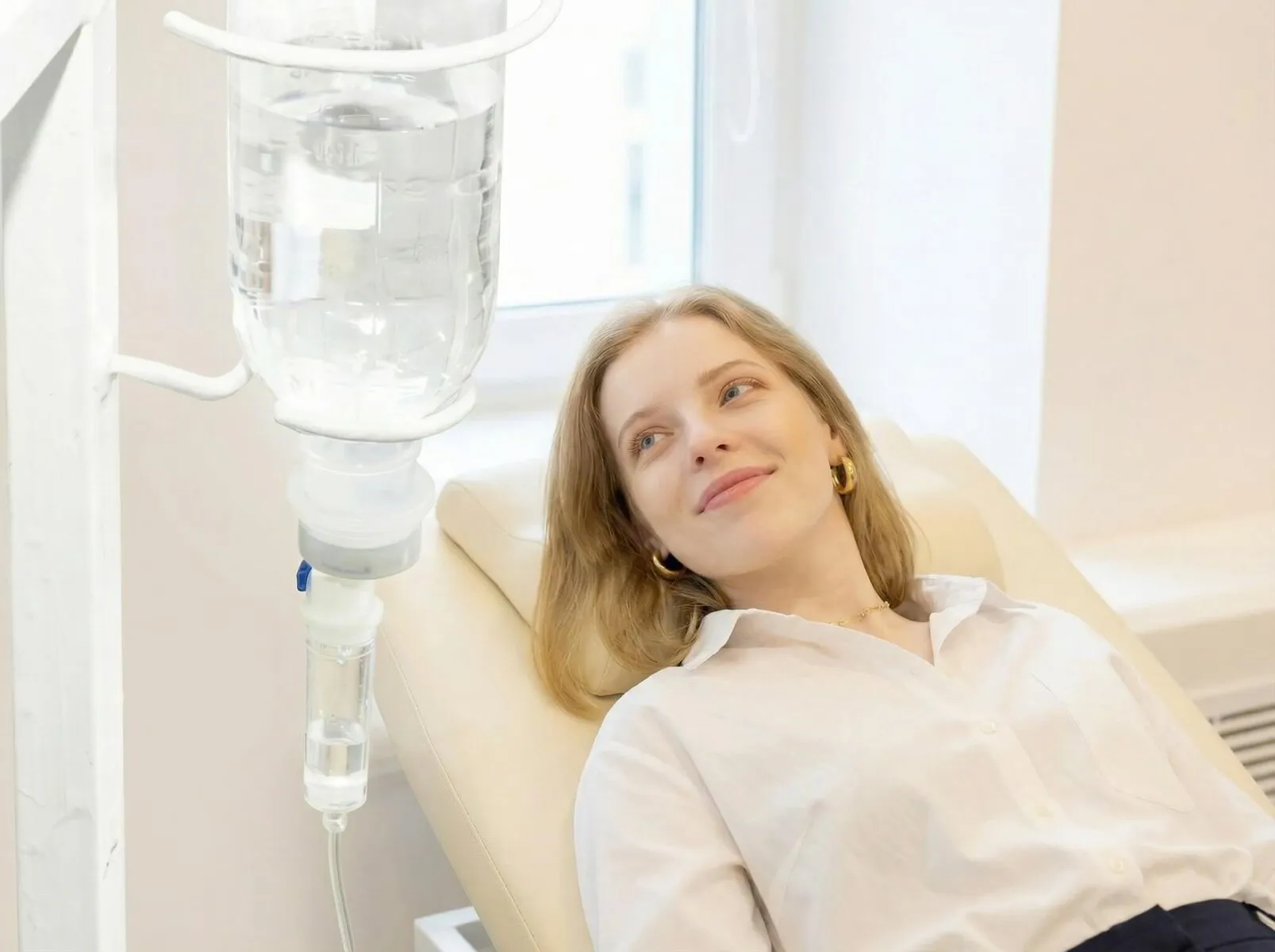 Entspannte Patientin auf einer Behandlungsliege mit Infusionstropf während einer Vitalstofftherapie